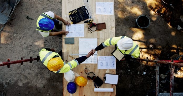 Blueprint, architecture and men at table shaking hands for collaboration, agreement and inspection from above. Construction, building team and contractor on site with floor plan, handshake and deal The HBF has warned that more needs to be done to tackle the Planning Staff Shortage