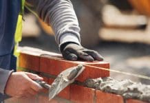 Construction’s skills crisis is a mismatch problem, not a shortage Bricklayer constructing stone wall using bricks, cement mortar mix and trowel