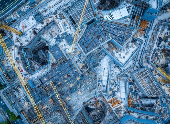 Top down view of a large modern building construction site with heavy machinery and complex steel structures. Ai in construction, especially digital construction, must be used carefully and cannot tackle every problem