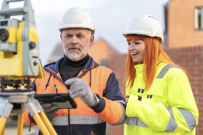 Male and female Engineers conducting site survey using surveying equipment at construction site New construction vocational GCSEs will open new pathways for students
