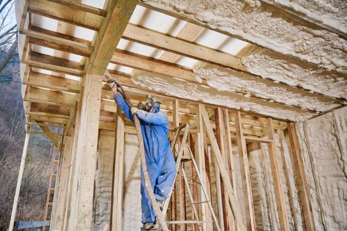 Worker spraying polyurethane foam insulation on ceiling beams in timber frame house The UK retrofit system is the focus of the NRH's latest report