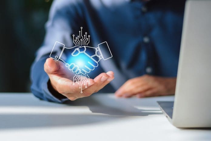 Human and AI Robotic Handshake Hologram Partnership Close-up of a businessman with an open palm supporting a glowing digital hologram of a handshake between a human and an artificial intelligence robot, symbolizing tech partnership, digital transformation, and human-AI collaboration