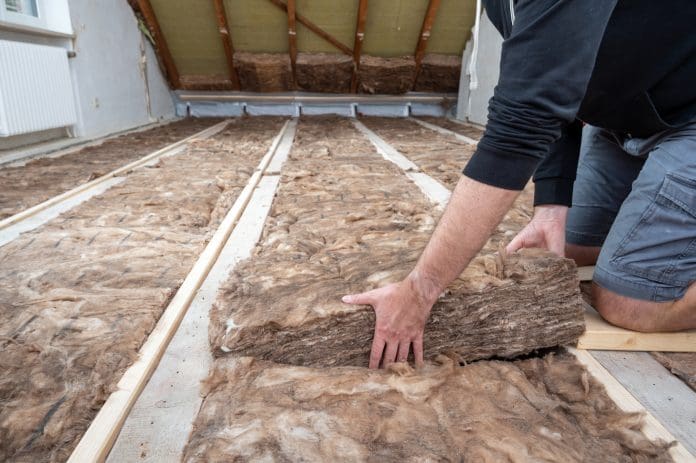 Man insulating the attic with rock wool. Home insulation schemes could be underestimating heat loss, research finds