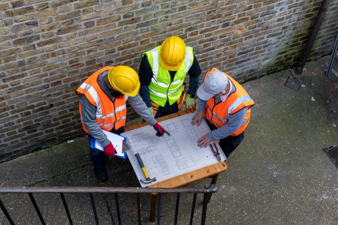 The architect with the building plan in discussion with the construction supervisors. Architects across the globe are reflecting on World Architecture Day
