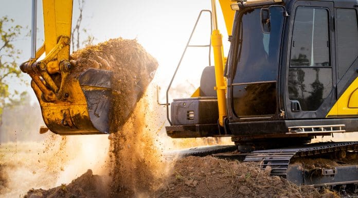 Close-up of excavator at construction site. Backhoe digging soil for earthwork and construction business. Excavating machine at work. Heavy machinery for earth moving and construction site development