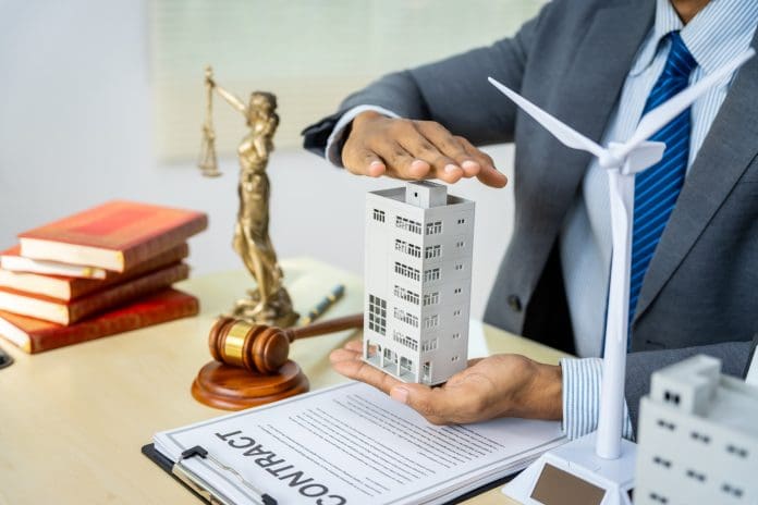 A male Asian lawyer in a formal suit works at his desk, focusing on contracts, legal matters, and urban planning issues such as building models, zoning, ordinances, and municipal regulations. Local authorities struggling to meet planning deadlines despite surge in PPA fees