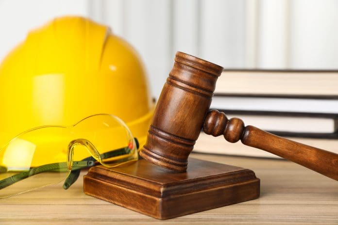 Accident at work. Gavel, goggles, hardhat and stack of books on wooden table, closeup Construction most unprepared for Employment Rights Act changes