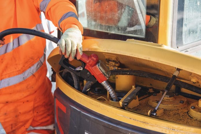 Mechanic in bright orange uniform refuels heavy machinery at construction site Reducing diesel reliance on construction sites: Where should smaller contractors start?