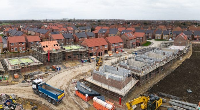 Aerial view above a construction site building new and affordable eco friendly houses with solar panels in the UK on green belt land