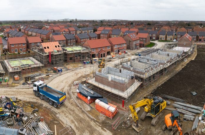 Aerial view directly above a new build housing construction site in the UK Aerial view above a construction site building new and affordable eco friendly houses with solar panels in the UK on green belt land