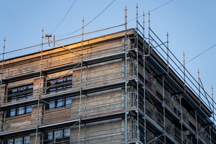 Tube and fitting scaffold surrounding an urban building corner for facade repair, window line access and external restoration operations Looking beyond construction: Rethinking retrofit’s workforce