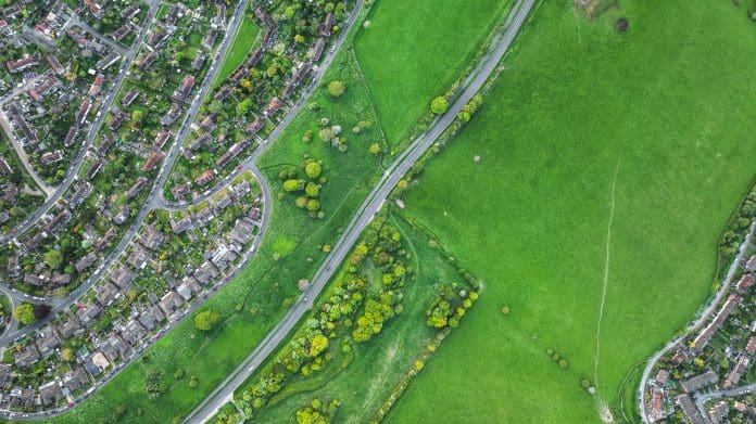 Aerial view of suburban neighborhood bordering lush green fields and a highway Browne Jacobson representatives discuss Reform UK and private planning