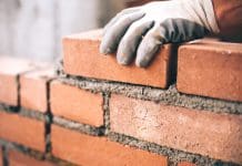 Rewiring council housebuilding: A programme for the 21st century Close up of industrial bricklayer installing bricks on construction site
