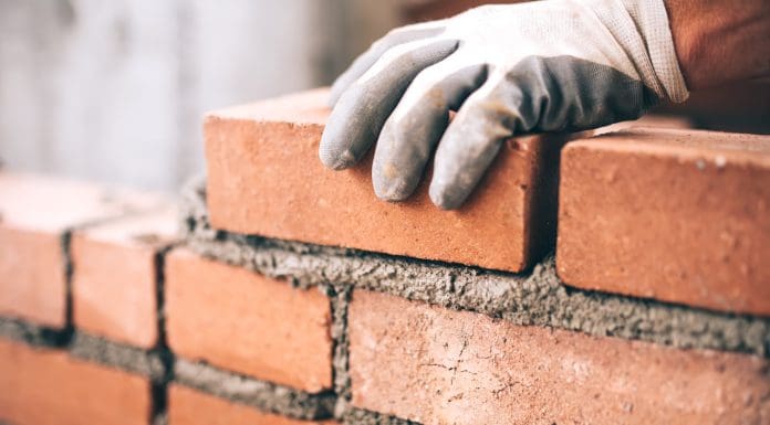 Close up of industrial bricklayer installing bricks on construction site