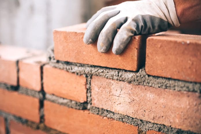 Close up of industrial bricklayer installing bricks on construction site Close up of industrial bricklayer installing bricks on construction site