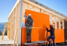 Impact of Part L and the Future Homes Standard on timber frame housebuilding wood-based panels being placed onto a timber frame house